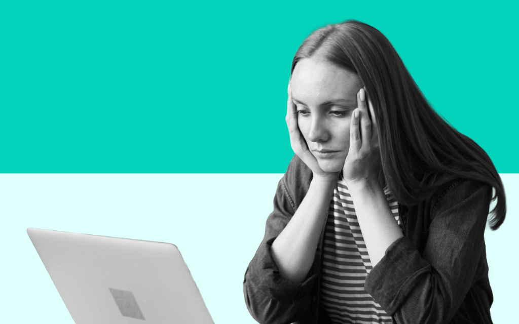 Stressed woman working at a computer in an office environment, representing workplace stress and mental health challenges